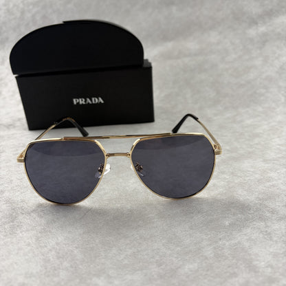 A pair of gold metal aviator sunglasses with dark lenses resting on a light grey textured background