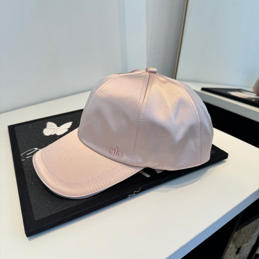Dusty pink satin baseball cap with a curved brim, featuring a minimalist adjustable back strap.