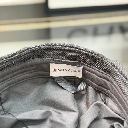 Close-up of a premium dark grey textured ivy cap with a white embroidered logo, high-quality fabric.