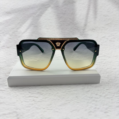 Oversized geometric sunglasses with green-to-yellow gradient lenses and gold metallic frame details.