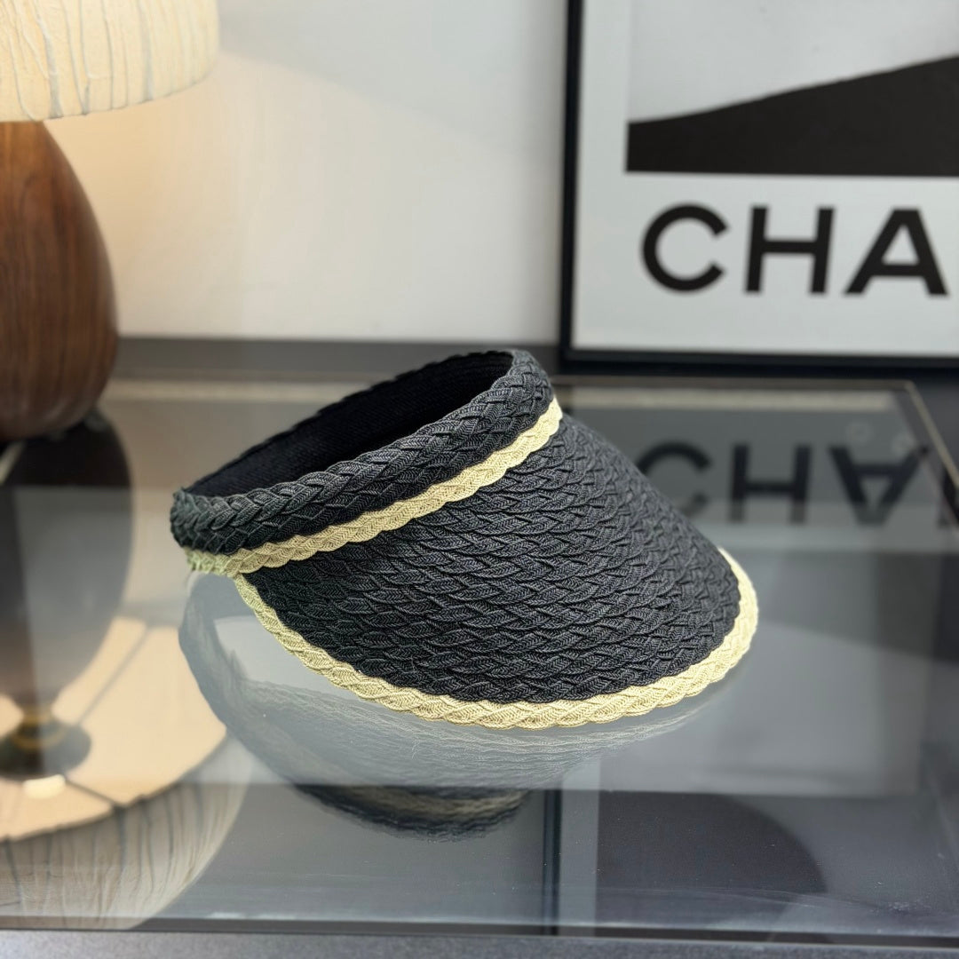 Close-up of a stylish woven straw sun visor with contrast border and white emblem detail.