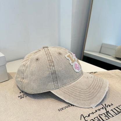 Distressed beige baseball cap with intricate floral letter embroidery and pearl details.