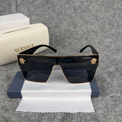 Oversized flat-top shield sunglasses with black lenses and decorative gold-tone metal side accents.