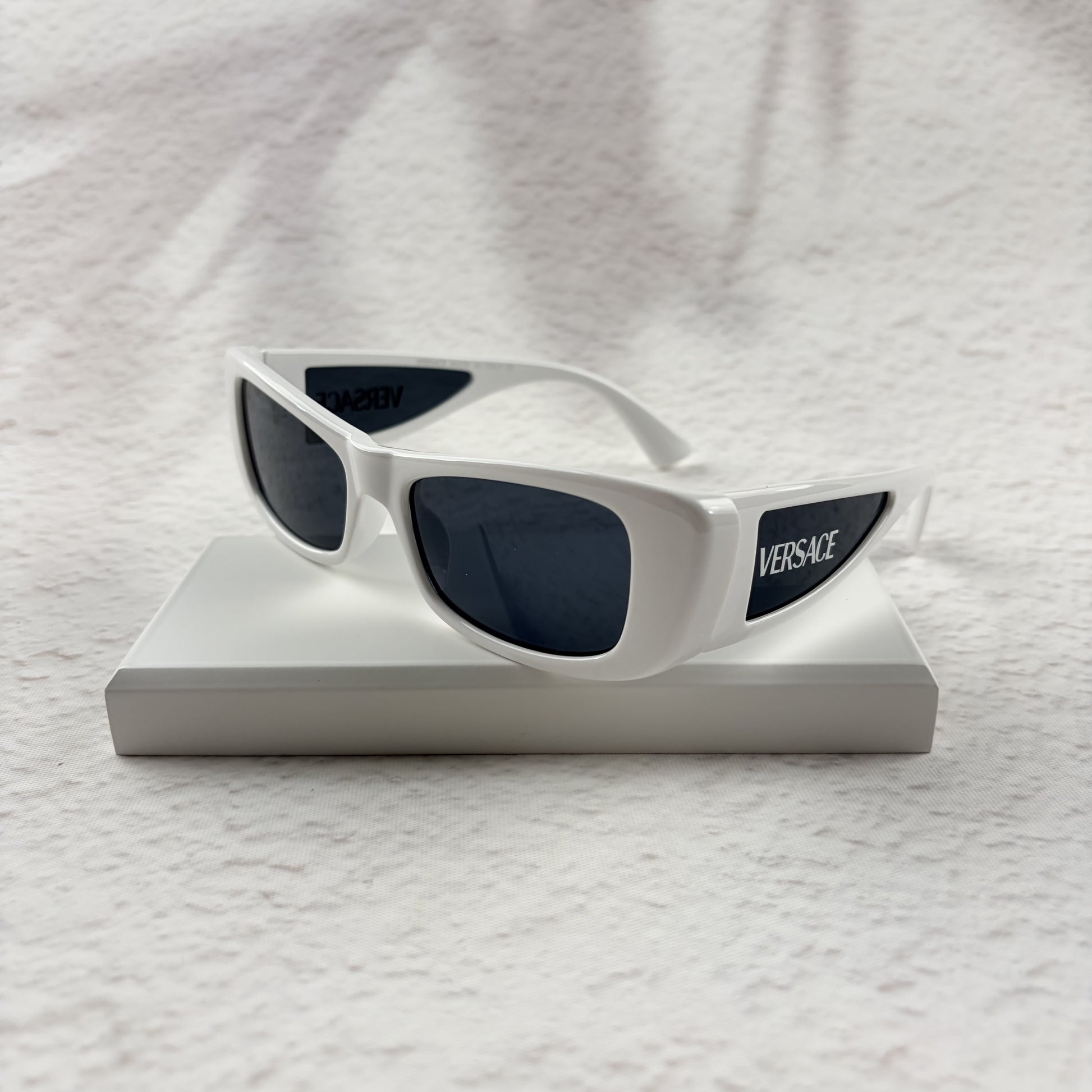 A pair of modern rectangular sunglasses with a bright white frame and dark tinted lenses.