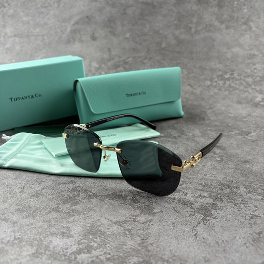 Rimless gradient sunglasses with gold-tone metal frames and black temple arms on a grey surface.