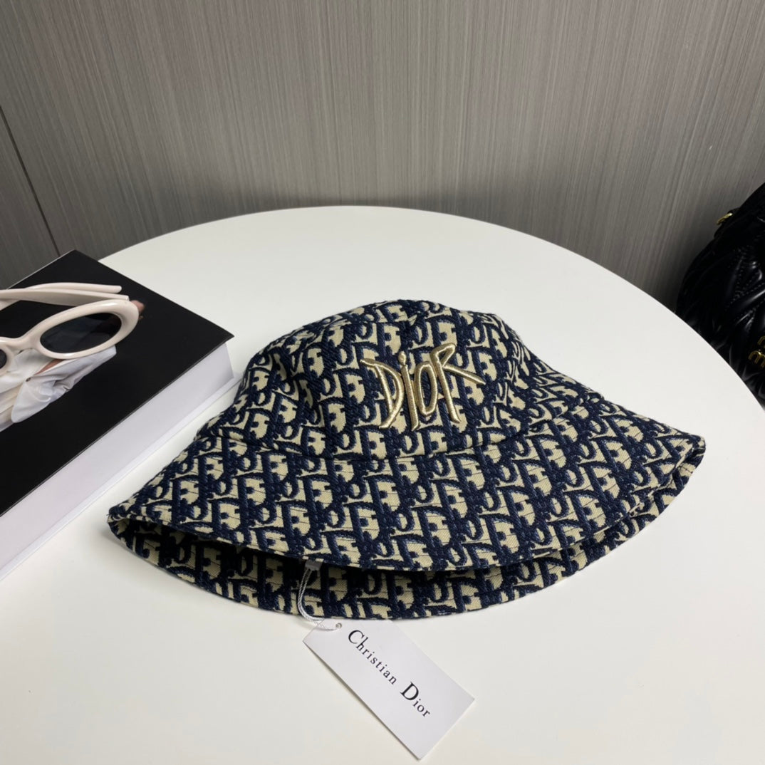 Close-up of a premium navy and beige monogram patterned bucket hat with central gold embroidery.
