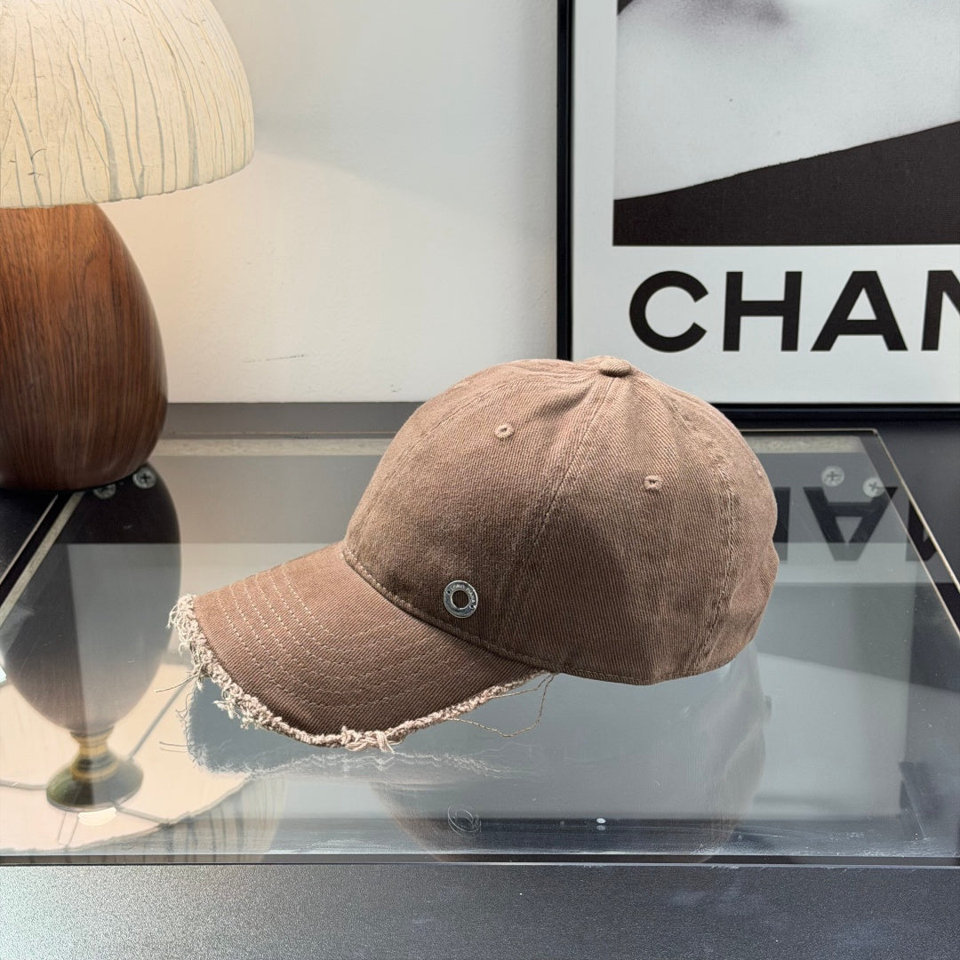Distressed brown cotton baseball cap with frayed brim and minimalist metal circular side detail.