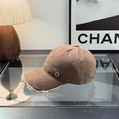 Distressed brown cotton baseball cap with frayed brim and minimalist metal circular side detail.