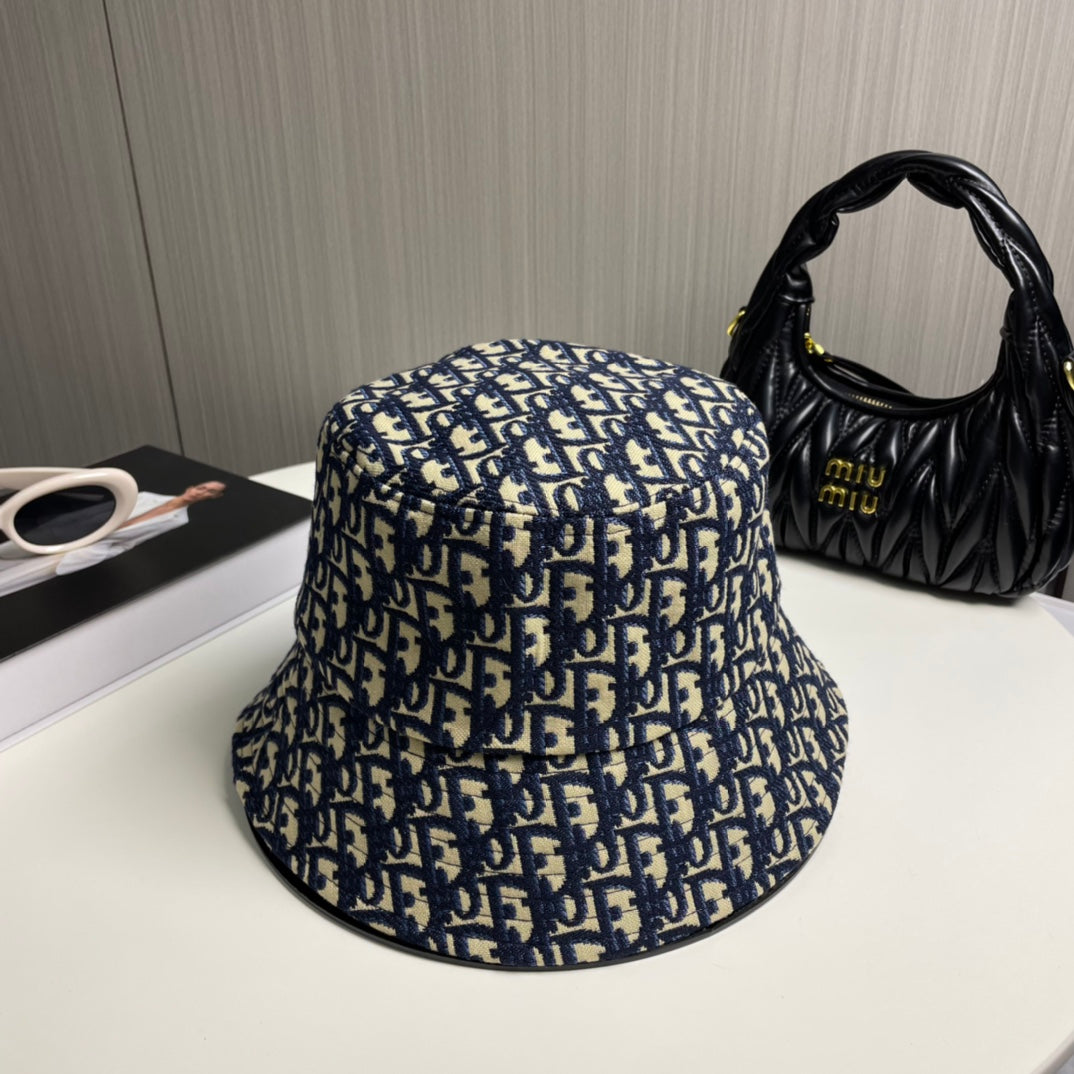 Close-up of a premium navy and beige monogram patterned bucket hat with central gold embroidery.
