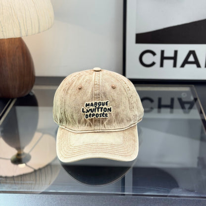 Vintage style distressed light brown denim baseball cap with embroidered letter patch on front.