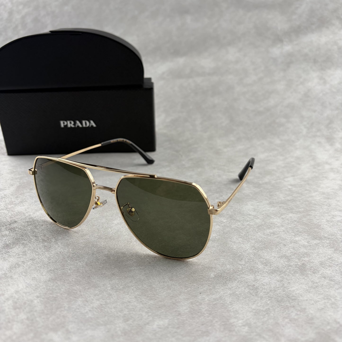 Classic gold-tone metal aviator sunglasses with tinted lenses, resting next to a protective case.