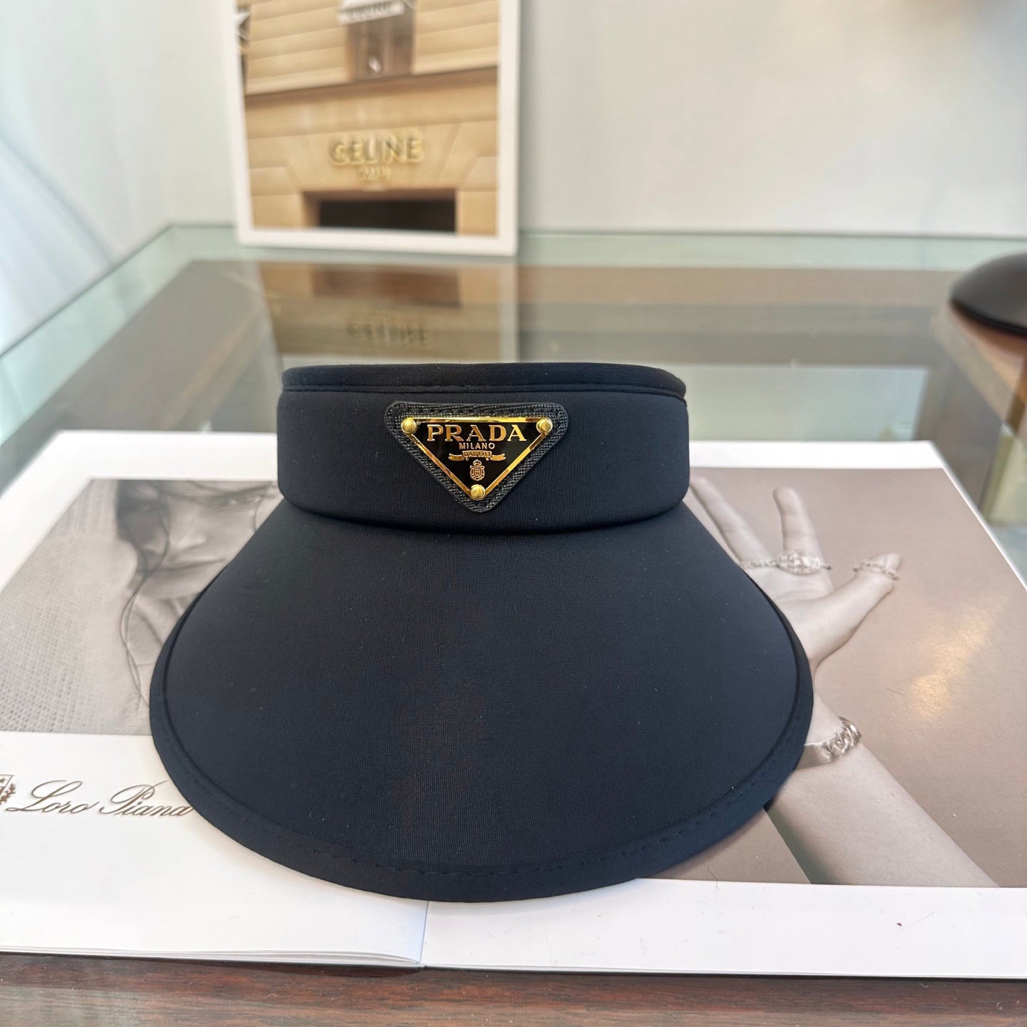 A sleek black wide-brim sun visor featuring a gold triangular emblem, designed for sun protection.