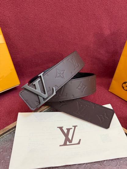 Close-up of a brown embossed leather belt featuring a matte metal buckle and patterned surface.