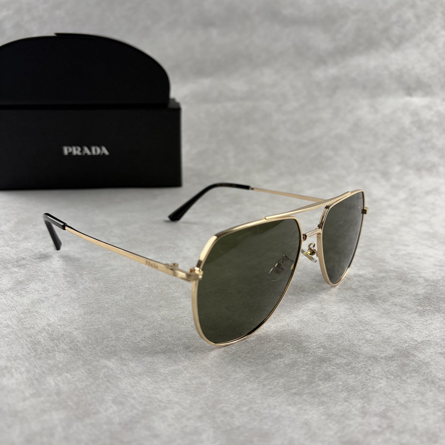 Classic gold-tone metal aviator sunglasses with tinted lenses, resting next to a protective case.