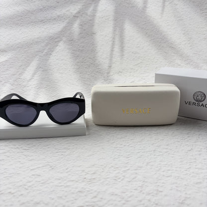 Black cat-eye sunglasses featuring gold-toned baroque temple embellishments on a white textured base
