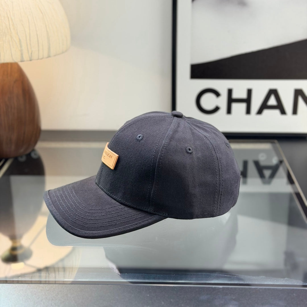 A structured black cotton baseball cap with a rectangular tan faux-leather patch on the front.