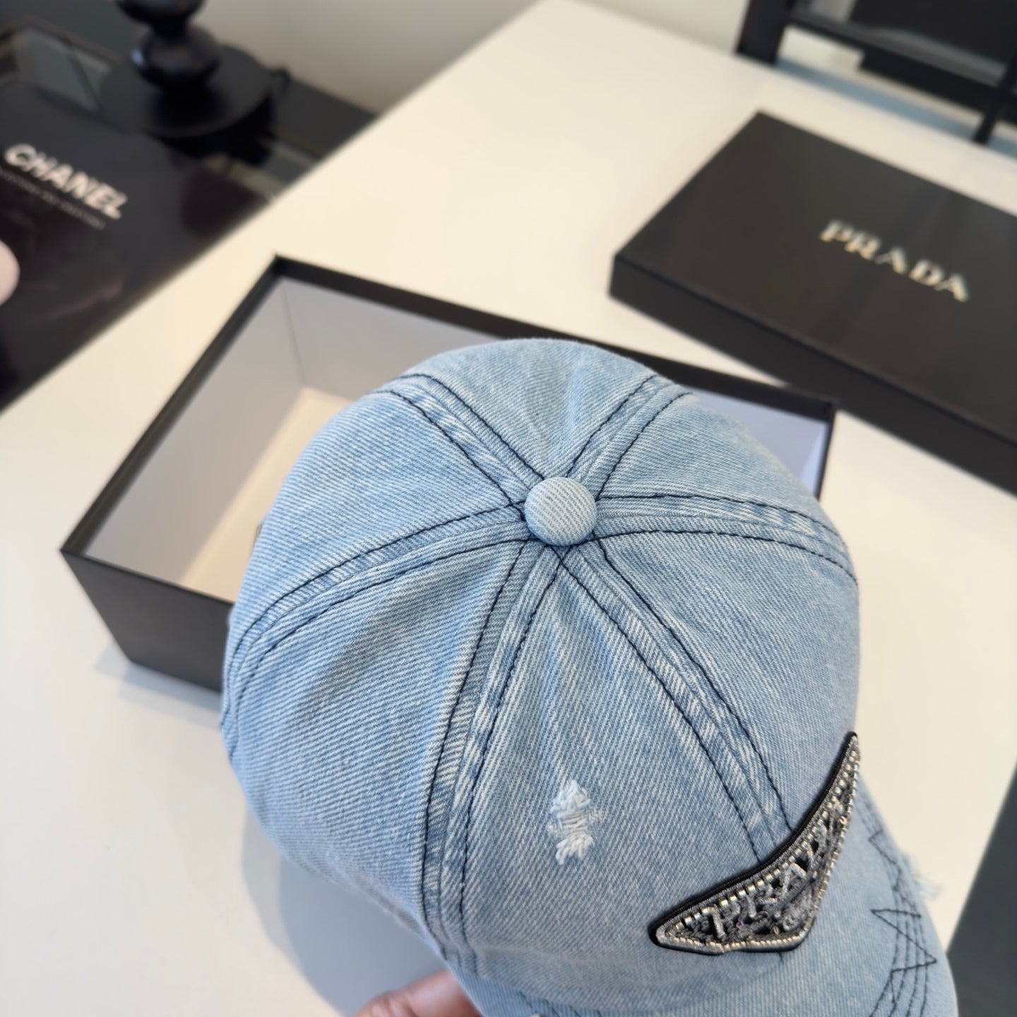 A light blue distressed denim baseball cap with a triangular embroidered patch on the front.