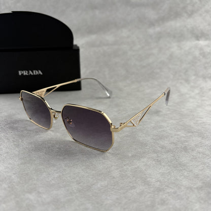 A pair of gold-toned geometric frame sunglasses with gradient lenses, displayed with a black protect