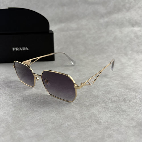 A pair of gold-toned geometric frame sunglasses with gradient lenses, displayed with a black protect
