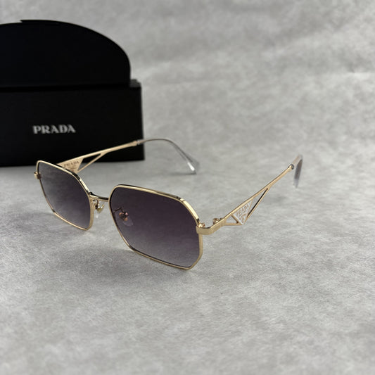 A pair of gold-toned geometric frame sunglasses with gradient lenses, displayed with a black protect