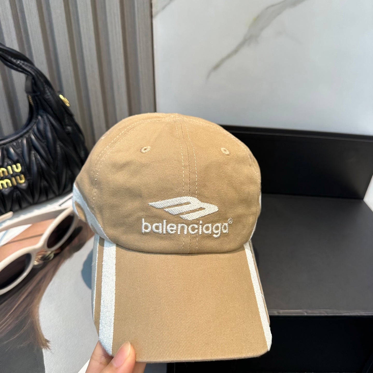 Tan cotton baseball cap with white side stripe detailing and embroidered logo on front.