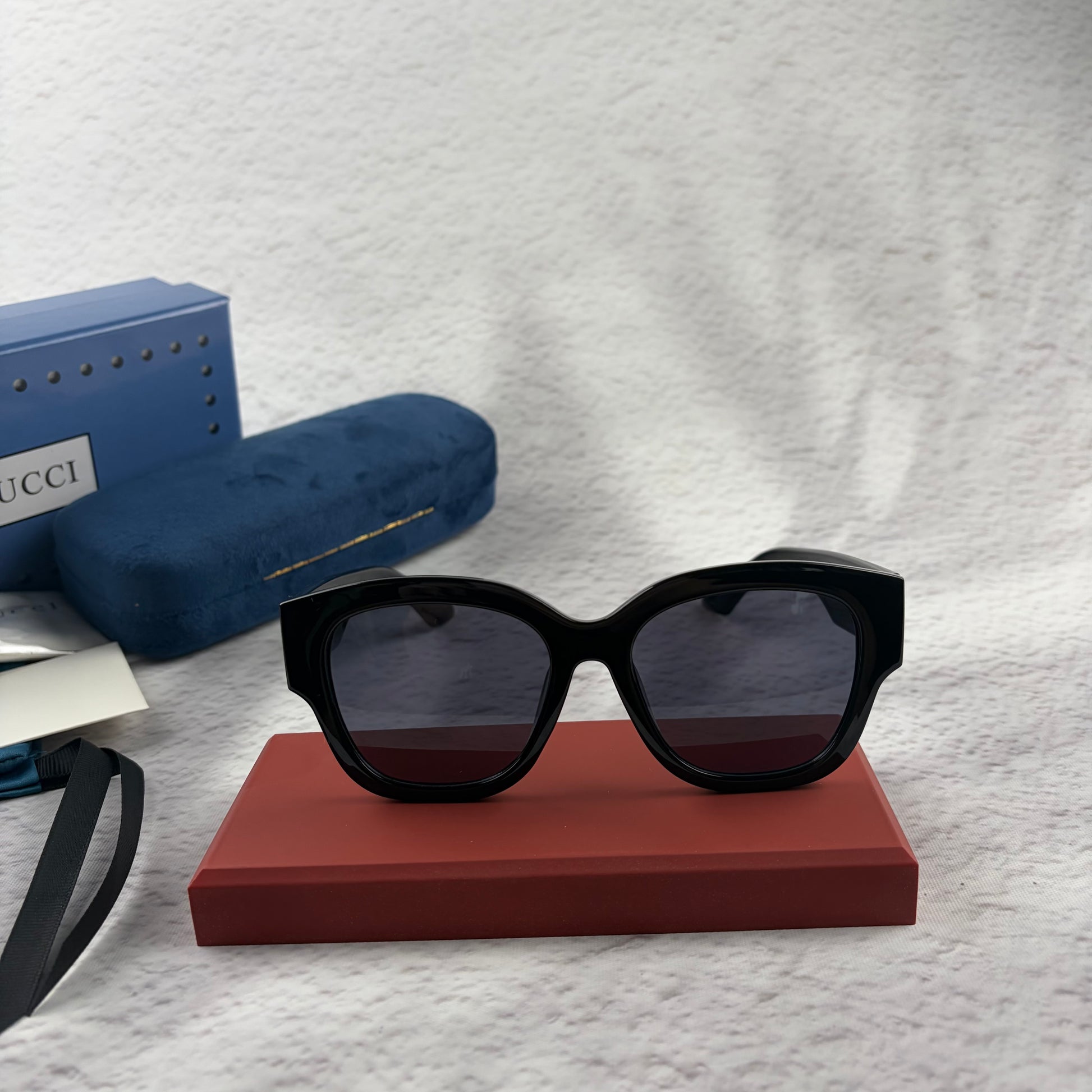 Oversized black frame sunglasses with dark gradient lenses and gold-tone logo detailing on temples.