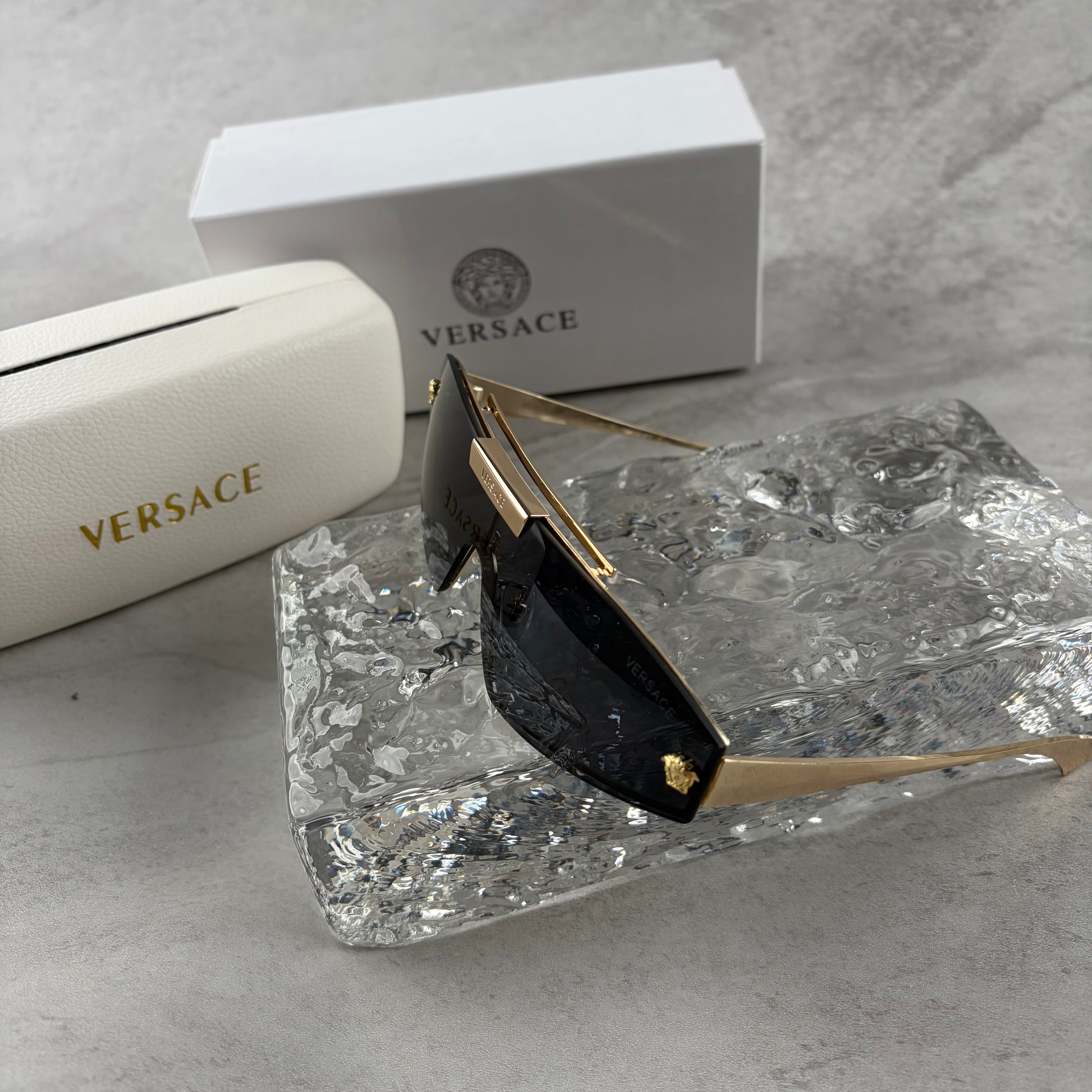 Gold metal frame shield sunglasses with dark lenses, featuring elegant temple detailing.
