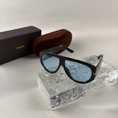 Black acetate oversized aviator sunglasses with blue tinted lenses resting on a clear ice-like block