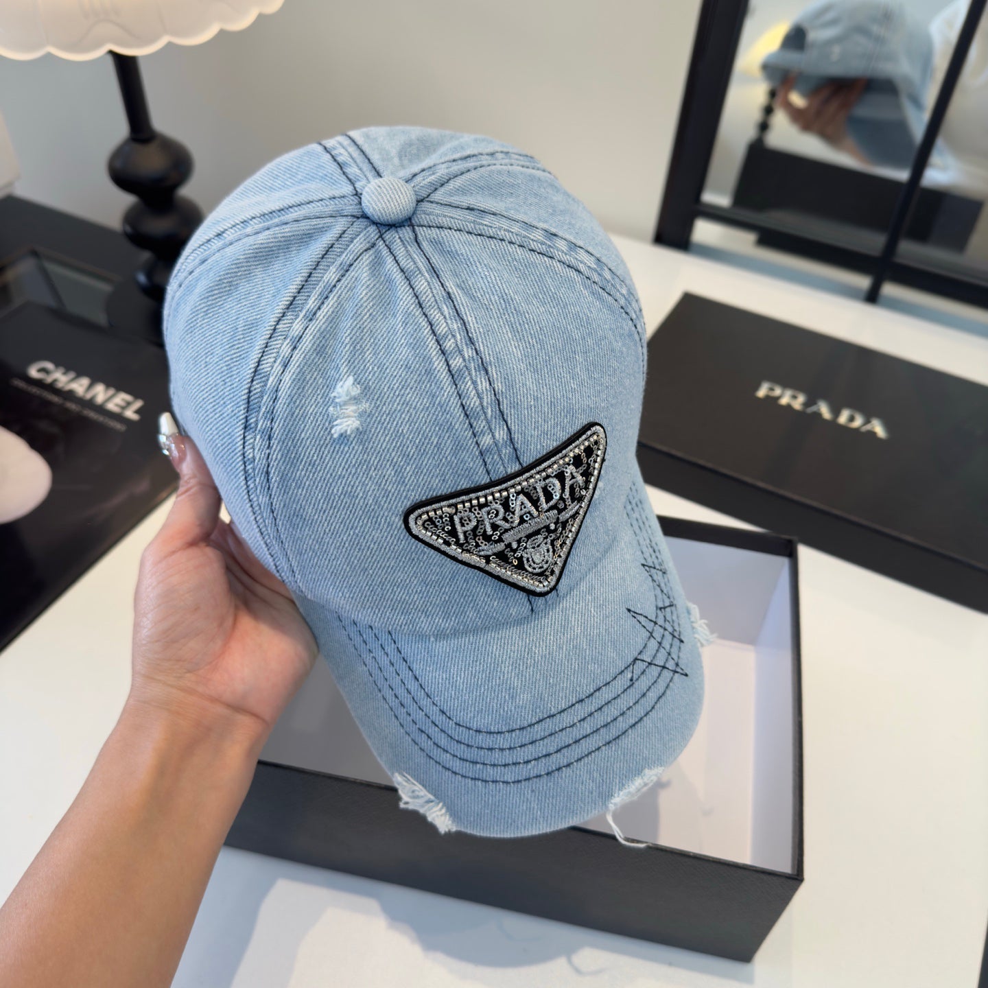 A light blue distressed denim baseball cap with a triangular embroidered patch on the front.