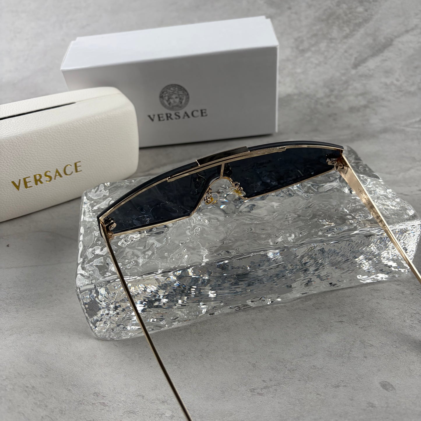 Gold metal frame shield sunglasses with dark lenses, featuring elegant temple detailing.