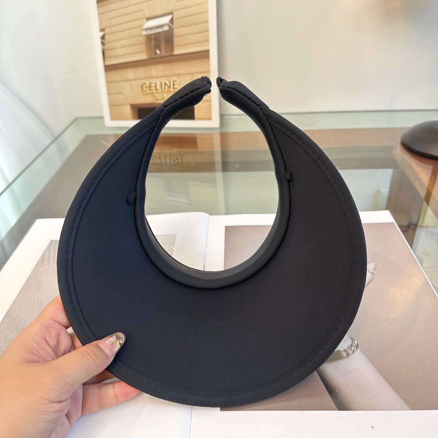 A sleek black wide-brim sun visor featuring a gold triangular emblem, designed for sun protection.