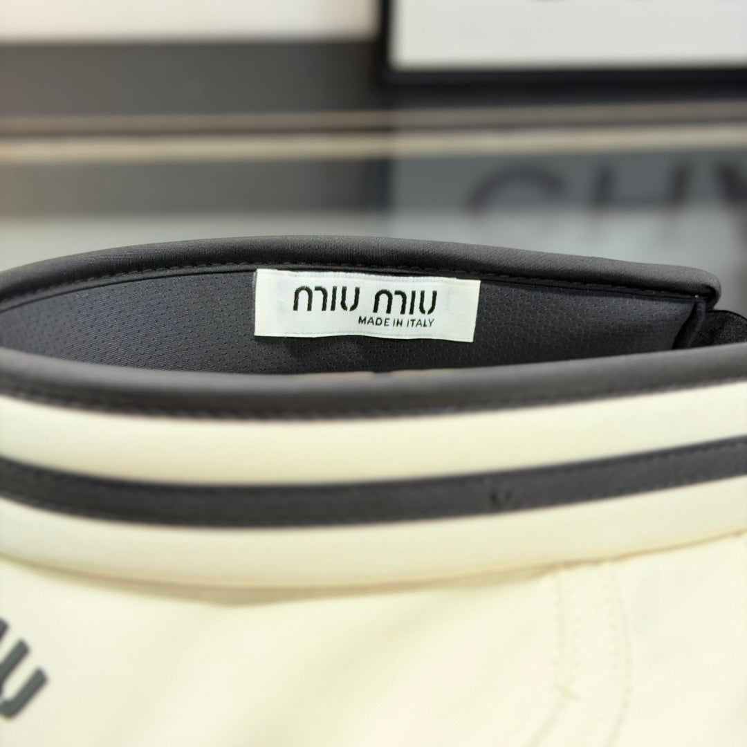 A stylish off-white open-top sports visor with black trim and embroidered text detailing.