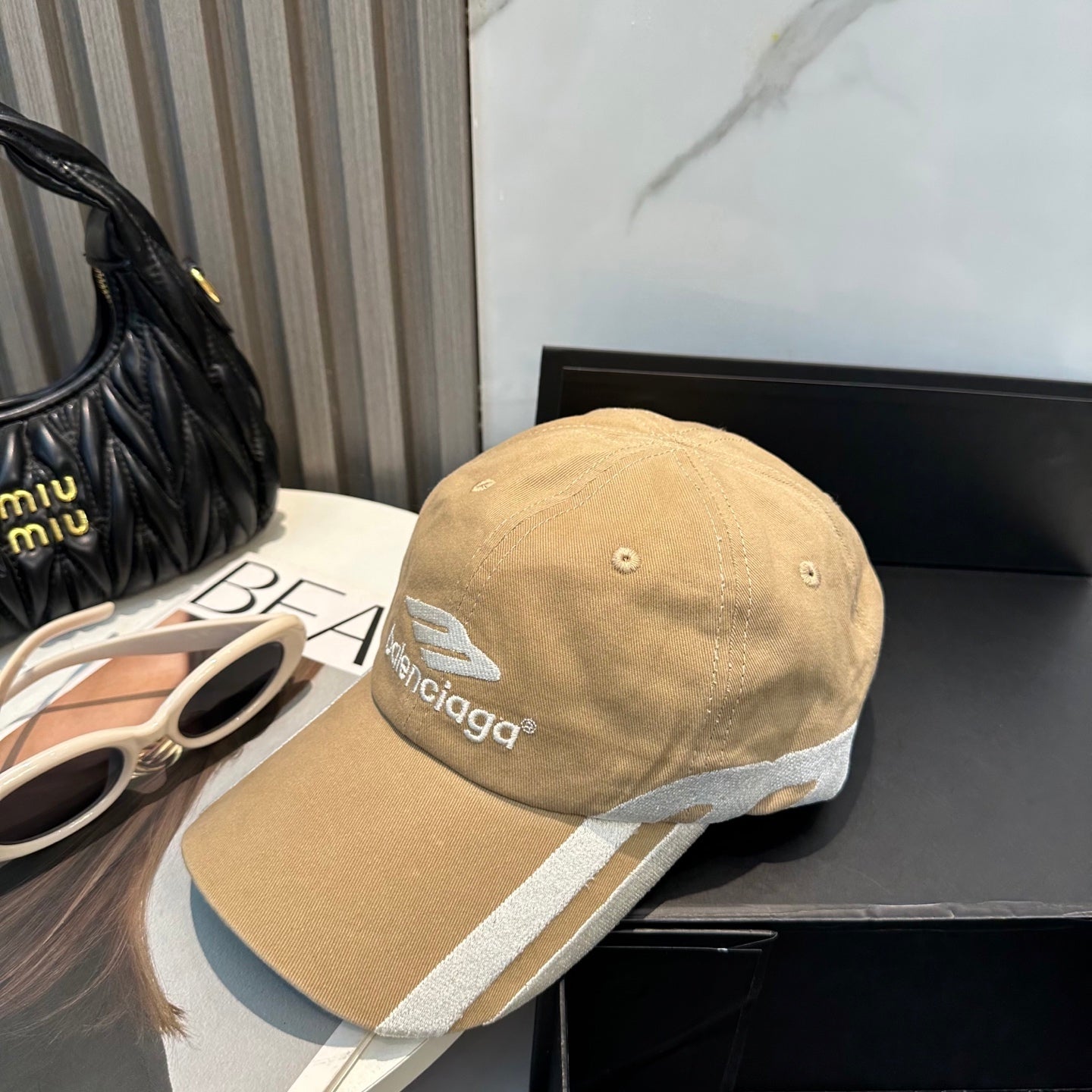 Tan cotton baseball cap with white side stripe detailing and embroidered logo on front.
