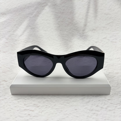 Black cat-eye sunglasses featuring gold-toned baroque temple embellishments on a white textured base
