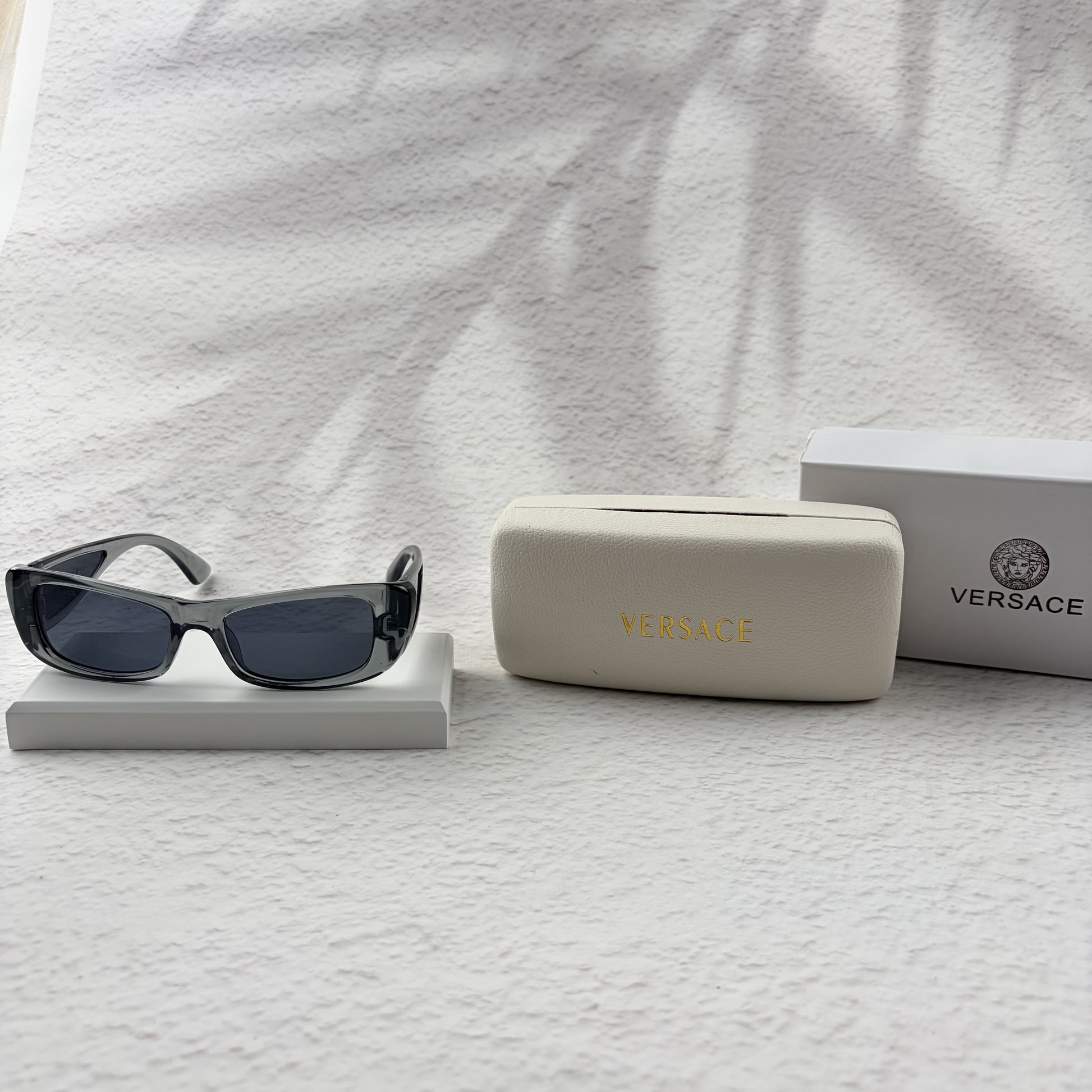 Modern rectangular sunglasses in translucent gray with dark tinted lenses, includes protective case.