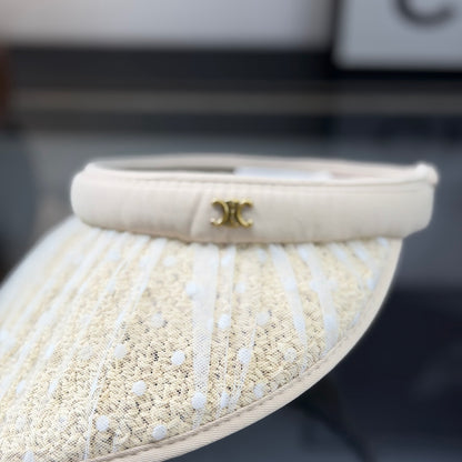 A beige straw sun visor with white polka dot mesh overlay and a gold metallic logo detail.