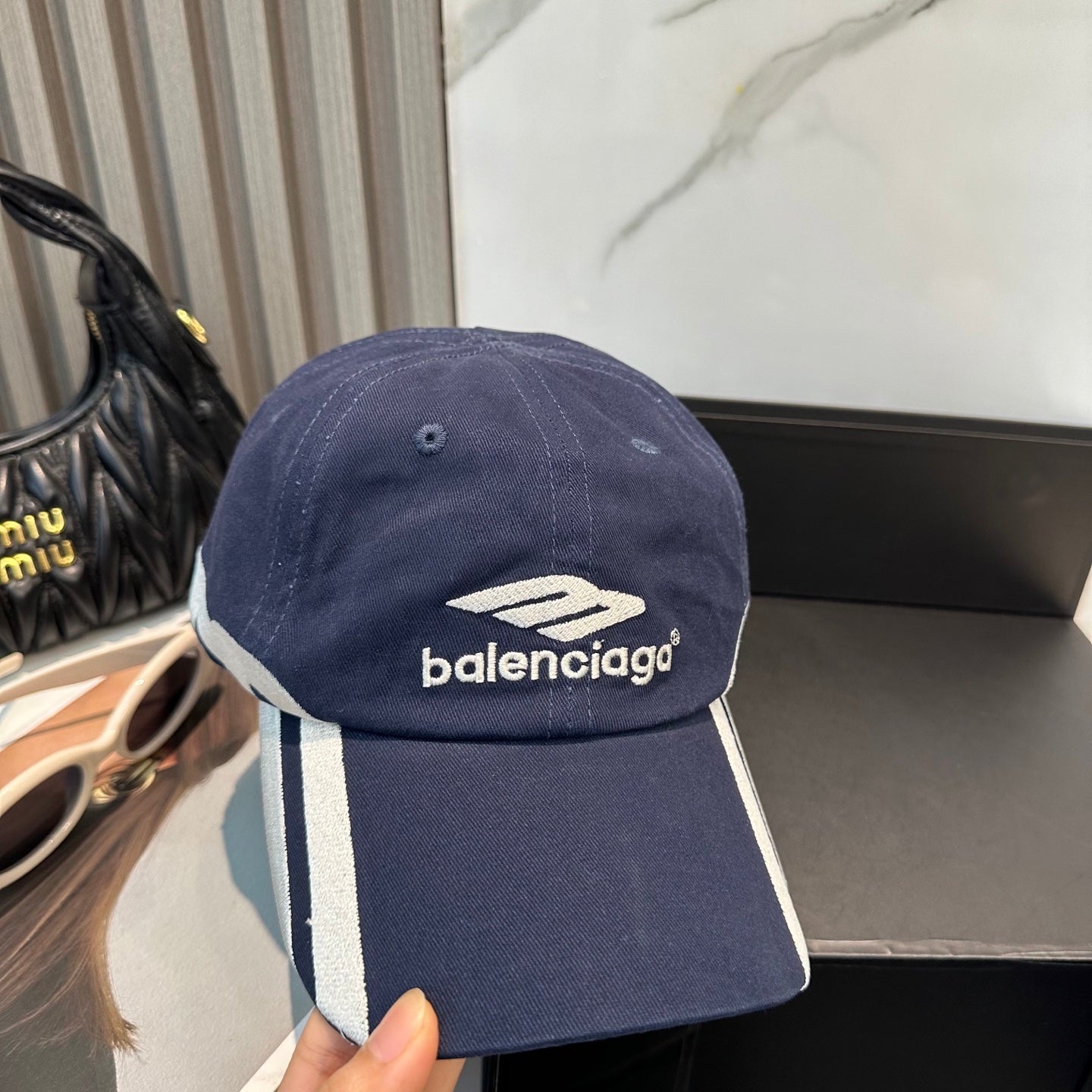 A navy blue cotton baseball cap with white embroidered logo and stripe detail on the side.