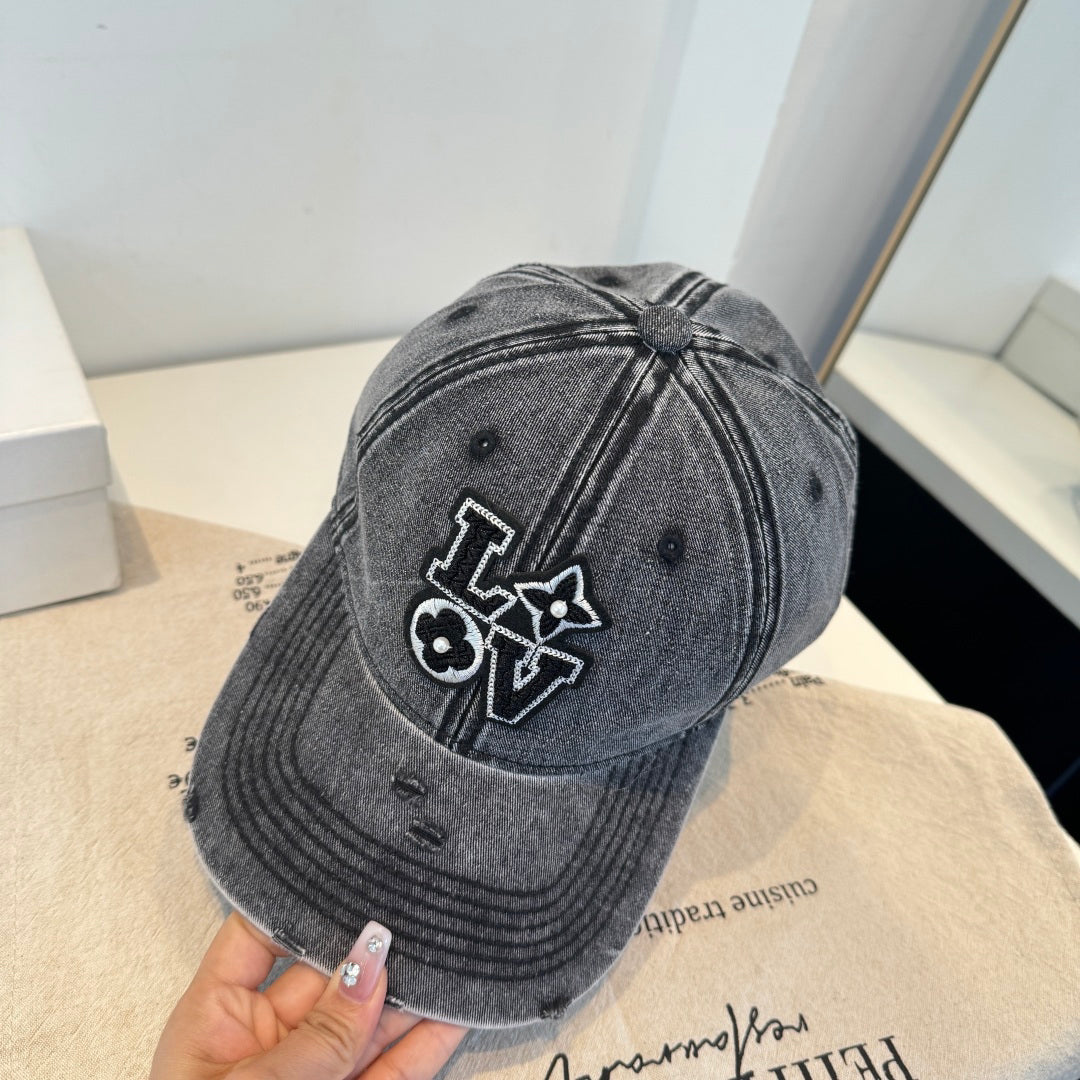 Distressed charcoal denim baseball cap with an embroidered LOVE patch featuring flower accents.