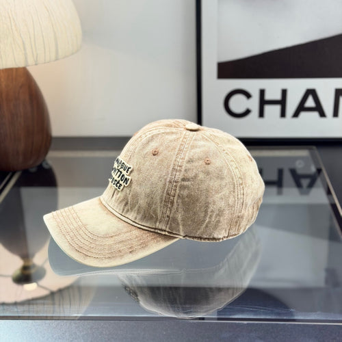 Vintage style distressed light brown denim baseball cap with embroidered letter patch on front.