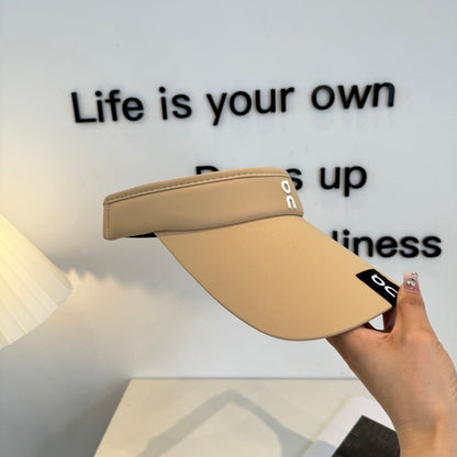 A beige lightweight sport visor with adjustable elastic band, featuring a minimalist logo design.