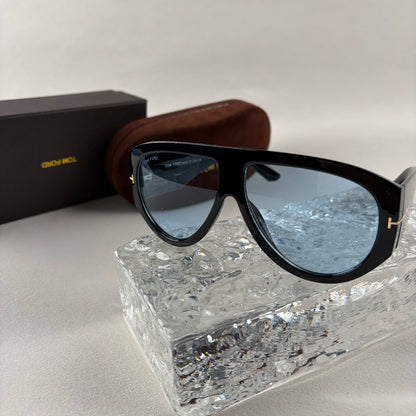 Black acetate oversized aviator sunglasses with blue tinted lenses resting on a clear ice-like block