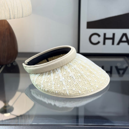A beige straw sun visor with white polka dot mesh overlay and a gold metallic logo detail.