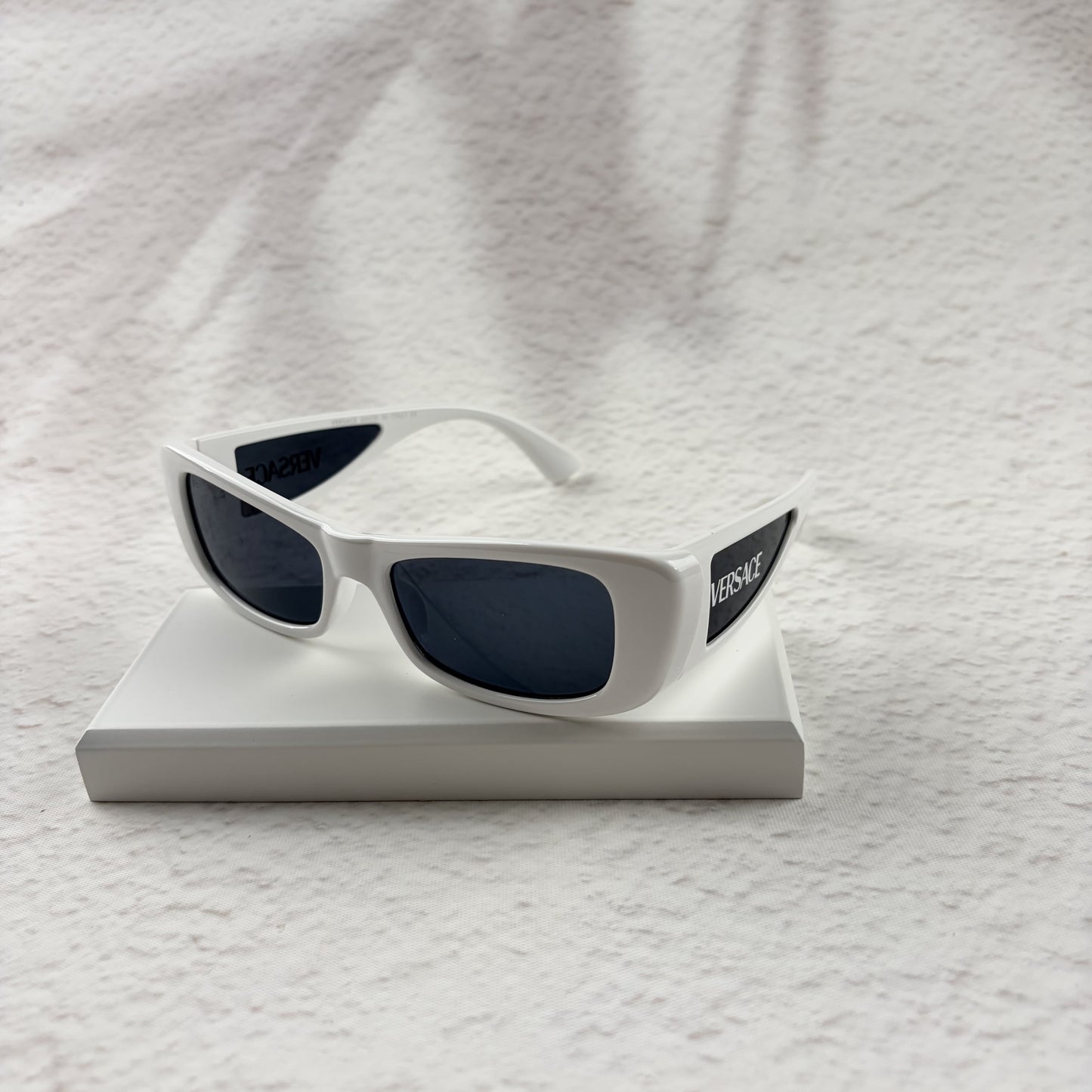 A pair of modern rectangular sunglasses with a bright white frame and dark tinted lenses.