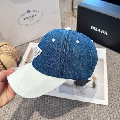 A stylish blue denim baseball cap with a white brim and a triangular metal-look logo patch.