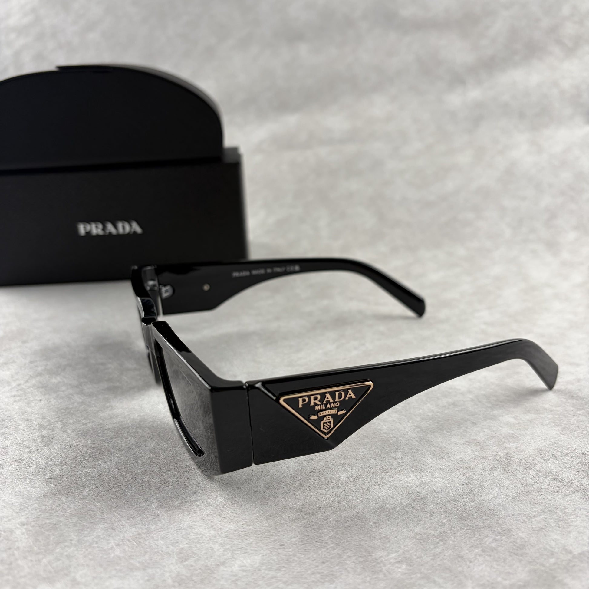 Modern black rectangular sunglasses with dark lenses and thick frame, isolated on a light background
