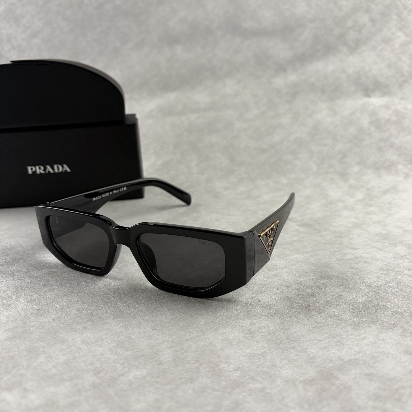 Modern black rectangular sunglasses with dark lenses and thick frame, isolated on a light background