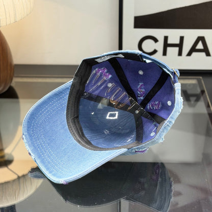 Distressed blue denim baseball cap with frayed detailing and a central stitched logo emblem.