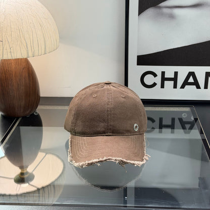 Distressed brown cotton baseball cap with frayed brim and minimalist metal circular side detail.