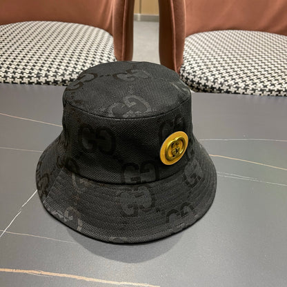 A black textured bucket hat with a circular gold emblem, featuring a monogrammed fabric design.