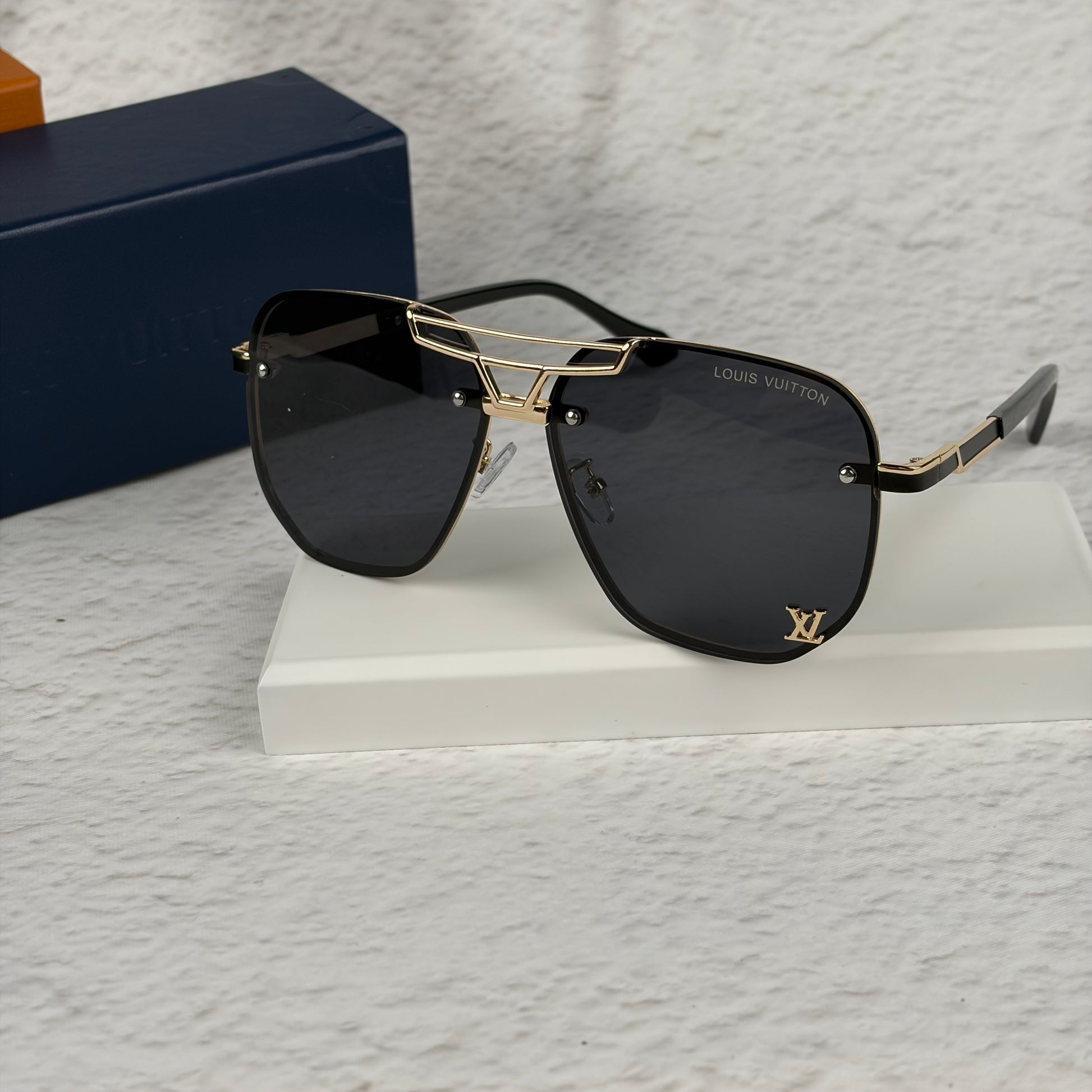 Modern aviator sunglasses with gold metal bridge, dark lenses, and black temple tips on display.